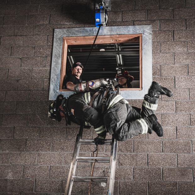 A firefighter uses TruBlue SafeLine for window bailout training